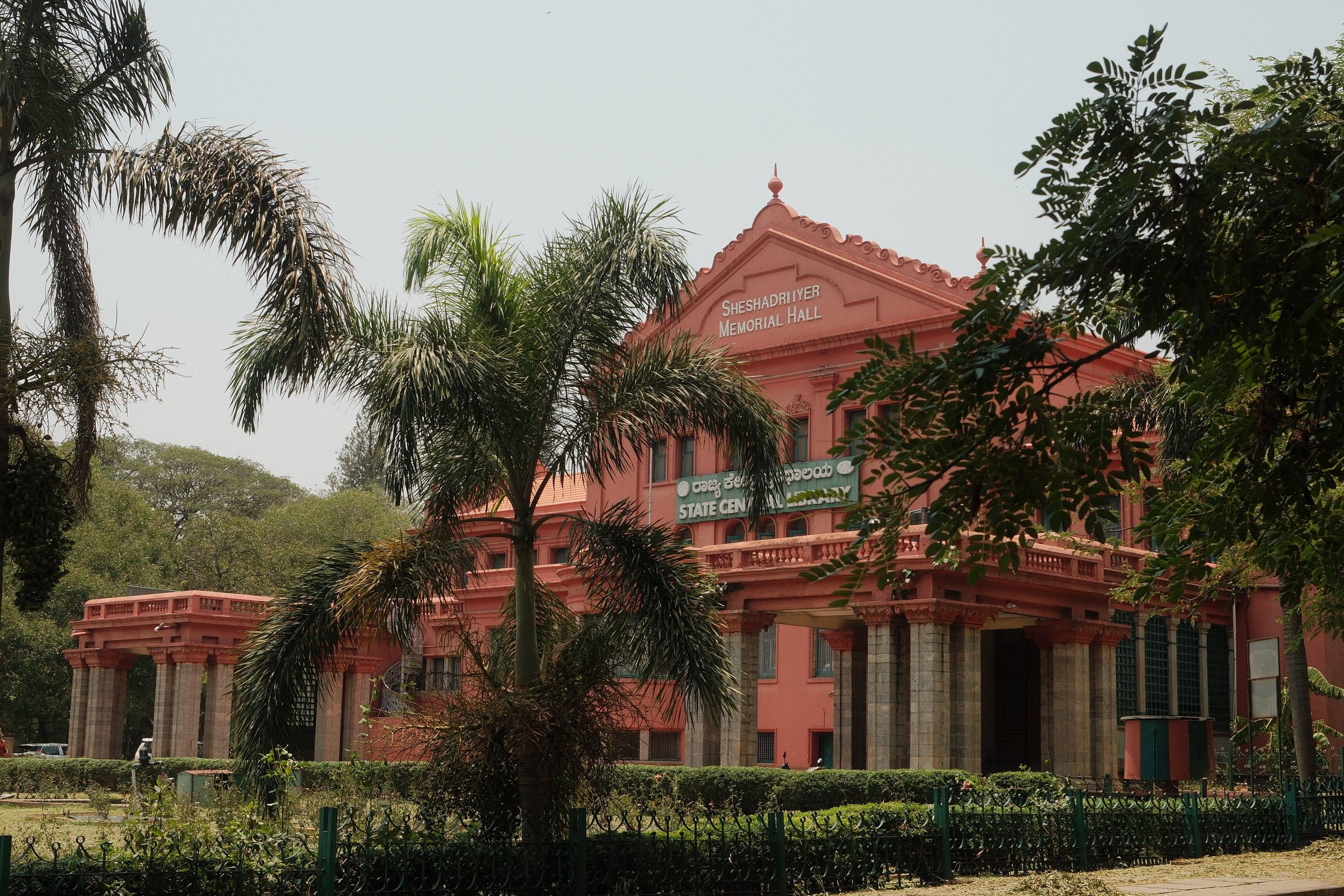 Sheshadri Iyer Memorial Hall, the State Central Library in Cubbon Park, framed through palm fronds.